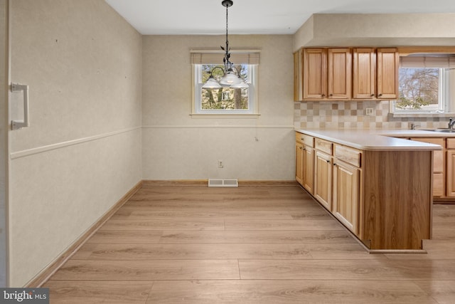 kitchen with light countertops, light wood-style flooring, visible vents, and a healthy amount of sunlight