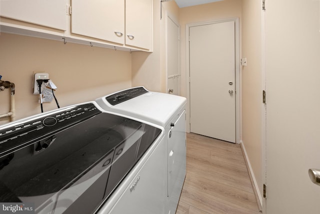 laundry room with light wood-type flooring, washing machine and dryer, cabinet space, and baseboards