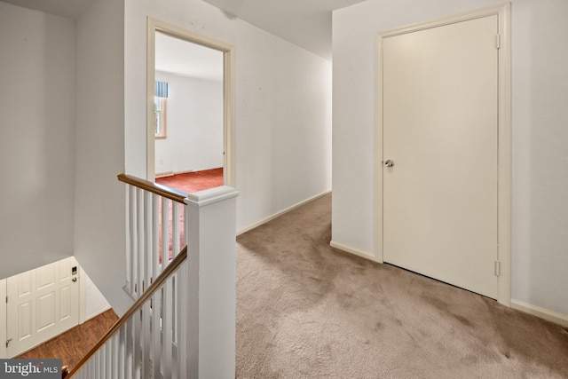 corridor with carpet flooring, an upstairs landing, and baseboards