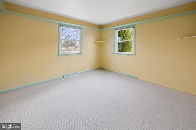 unfurnished room with carpet floors, visible vents, and baseboards