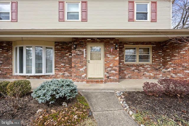 property entrance with a porch and brick siding