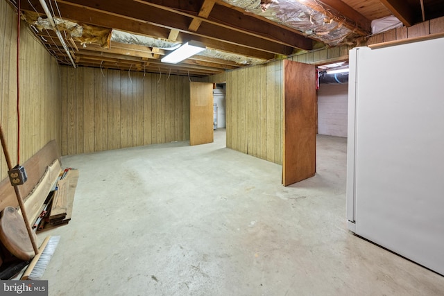 unfinished below grade area featuring freestanding refrigerator and wooden walls