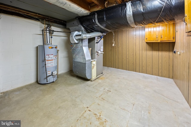 unfinished basement featuring concrete block wall, gas water heater, and heating unit