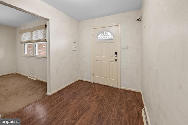 foyer entrance with baseboards, visible vents, and wood finished floors