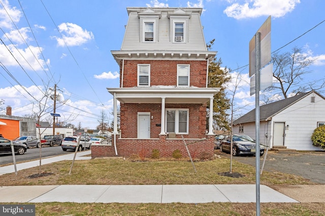 victorian home featuring brick siding and a front yard