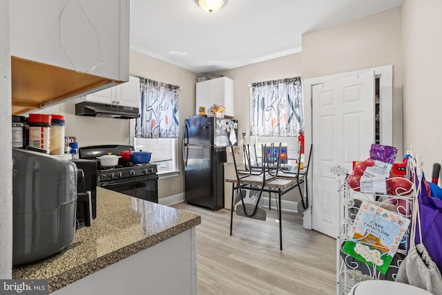 kitchen featuring baseboards, black appliances, under cabinet range hood, white cabinetry, and light wood-type flooring