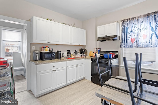 kitchen featuring black appliances, white cabinets, light countertops, under cabinet range hood, and light wood-type flooring