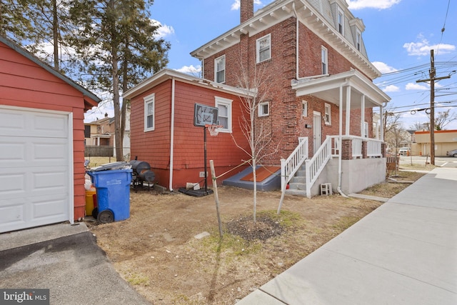 view of front of home with brick siding, a chimney, and a garage