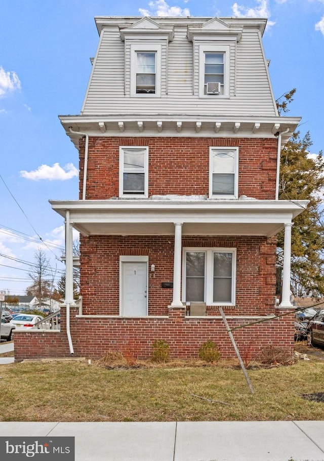 victorian home with brick siding, covered porch, and a front yard