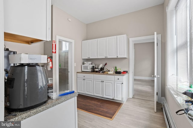 kitchen featuring white cabinetry, light wood-style flooring, plenty of natural light, and white microwave