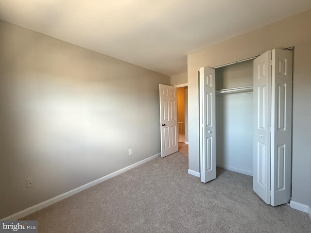 unfurnished bedroom with carpet, a closet, and baseboards