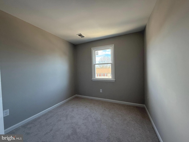 carpeted spare room featuring baseboards and visible vents