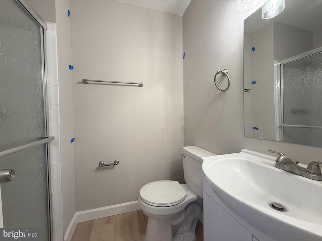 bathroom featuring toilet, a stall shower, vanity, wood finished floors, and baseboards