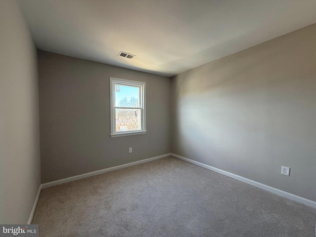 carpeted empty room featuring baseboards and visible vents