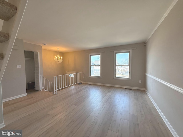 empty room with visible vents, light wood-style floors, baseboards, and a chandelier