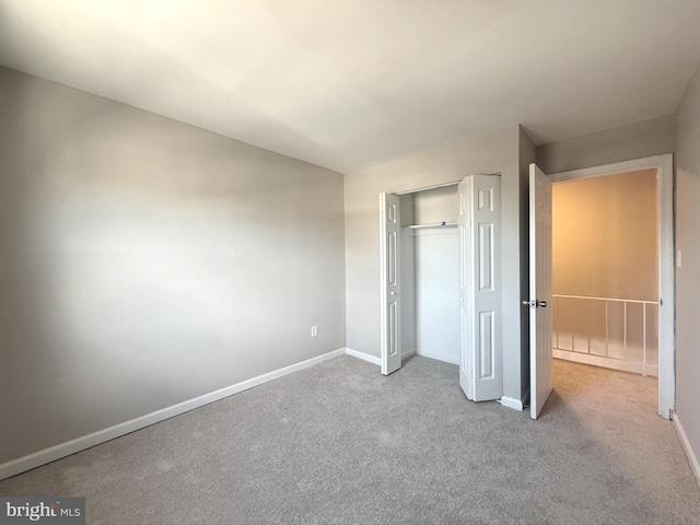 unfurnished bedroom featuring carpet, a closet, vaulted ceiling, and baseboards