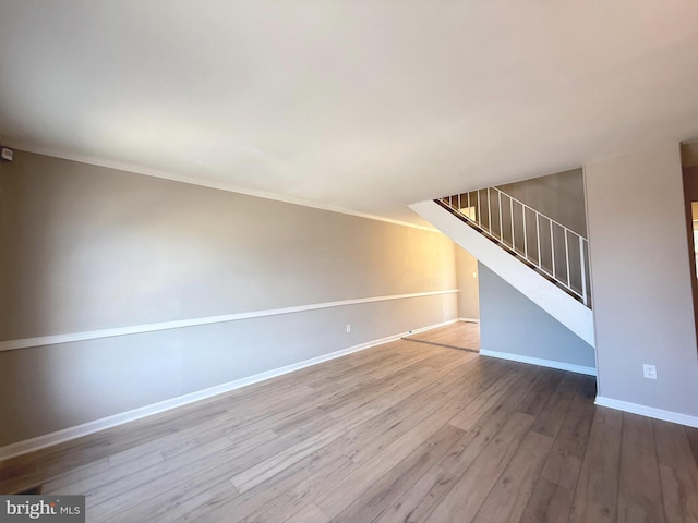 unfurnished living room with baseboards, stairway, and wood finished floors