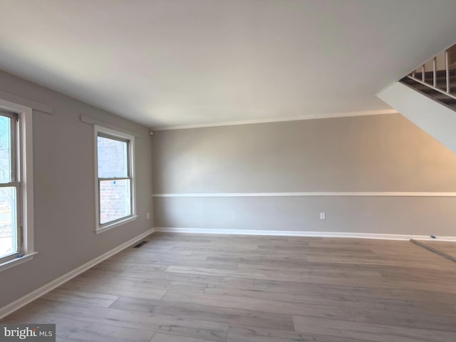 empty room featuring visible vents, baseboards, and wood finished floors