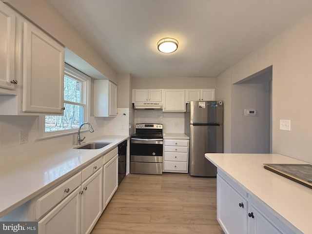 kitchen with under cabinet range hood, a sink, white cabinetry, appliances with stainless steel finishes, and backsplash