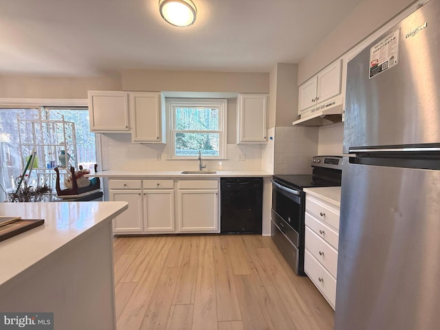 kitchen featuring under cabinet range hood, stainless steel appliances, a sink, white cabinetry, and light countertops