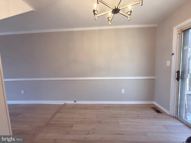 unfurnished dining area with light wood finished floors, baseboards, visible vents, crown molding, and a chandelier