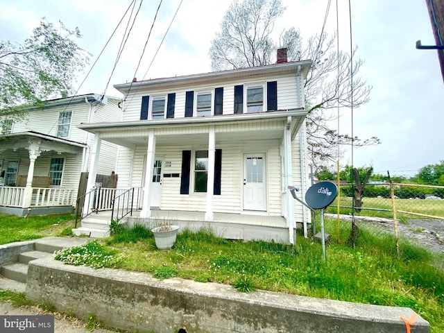 view of front facade with covered porch, fence, and a chimney