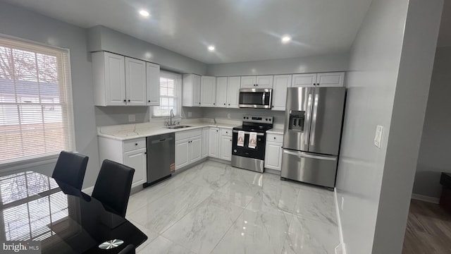 kitchen with baseboards, recessed lighting, white cabinets, stainless steel appliances, and a sink