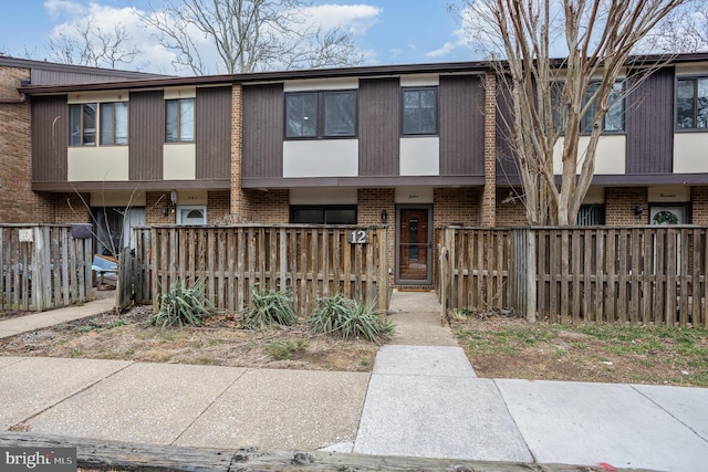 townhome / multi-family property with a fenced front yard and brick siding