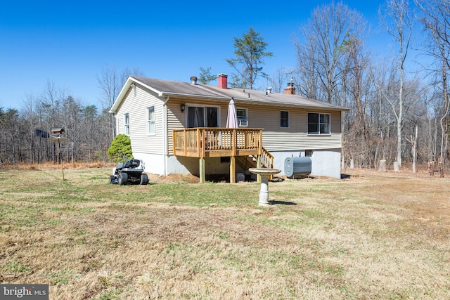 back of property with a yard, a chimney, a wooden deck, and heating fuel