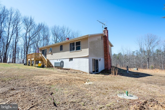 back of house with heating fuel, stairs, a chimney, and a deck