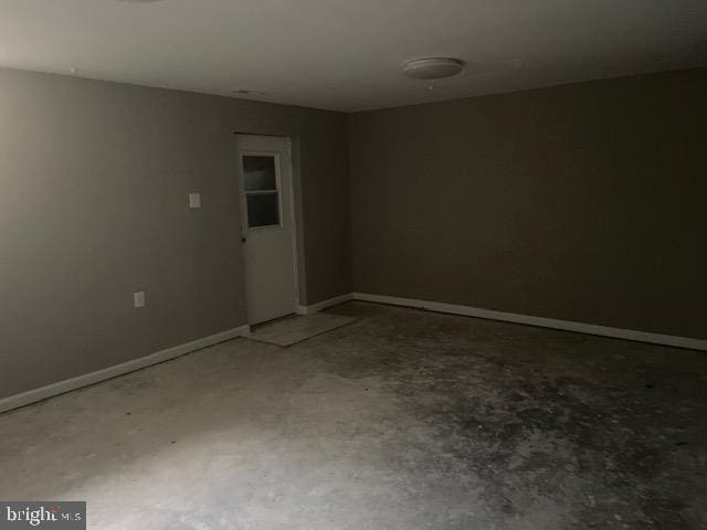 empty room featuring unfinished concrete floors and baseboards