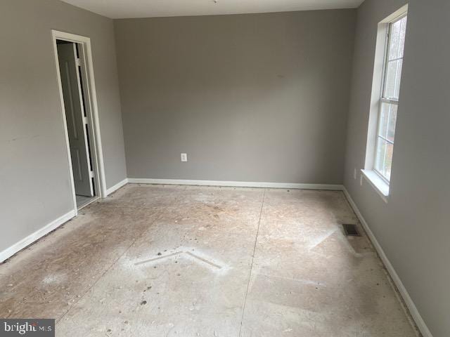 spare room featuring a wealth of natural light, visible vents, and baseboards