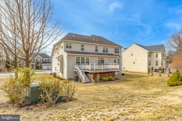 back of property with stairs, a deck, and a lawn