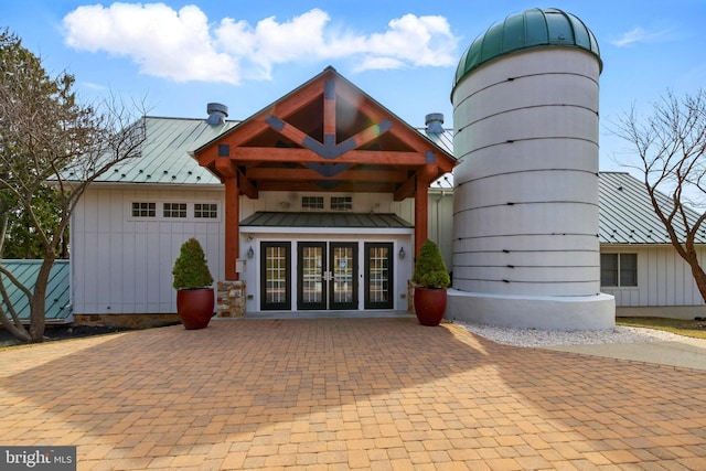 property entrance with a standing seam roof, french doors, board and batten siding, and metal roof