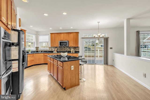 kitchen featuring decorative backsplash, a center island, light wood finished floors, and stainless steel appliances