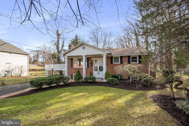 greek revival inspired property with a chimney, fence, a front lawn, and brick siding