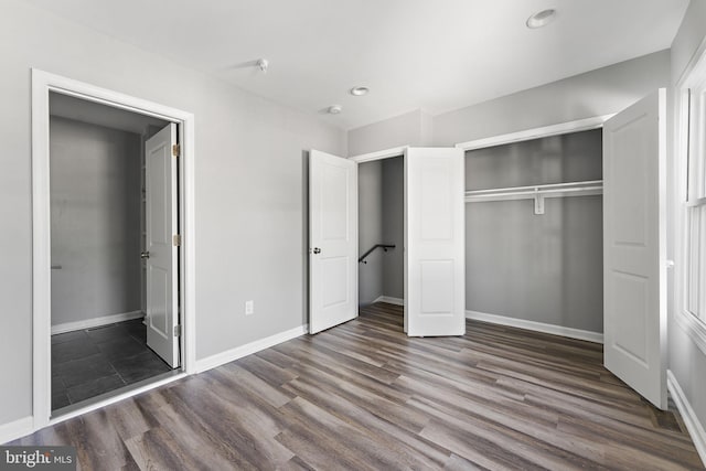 unfurnished bedroom with a closet, recessed lighting, dark wood finished floors, and baseboards