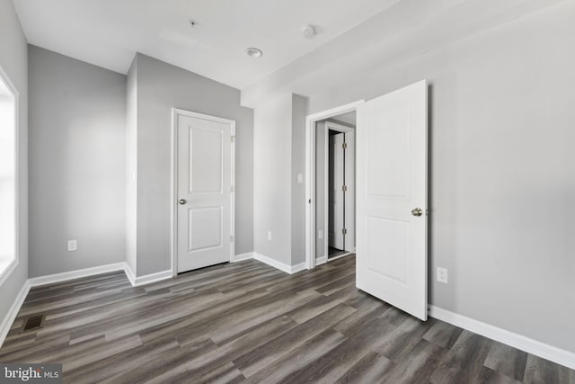 unfurnished bedroom featuring dark wood finished floors, visible vents, and baseboards