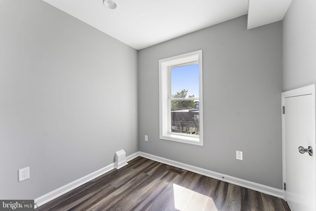 empty room with visible vents, baseboards, and dark wood-style flooring