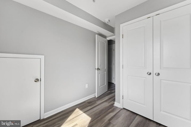 unfurnished bedroom featuring a closet, baseboards, and wood finished floors