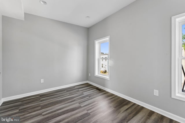 unfurnished room with a wealth of natural light, dark wood-style flooring, and baseboards