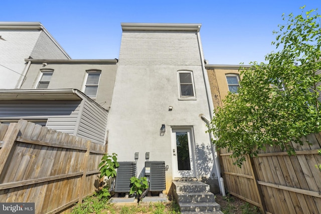 back of property with fence, central AC unit, and stucco siding