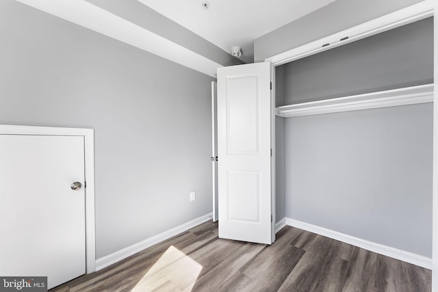 unfurnished bedroom featuring a closet, baseboards, and wood finished floors