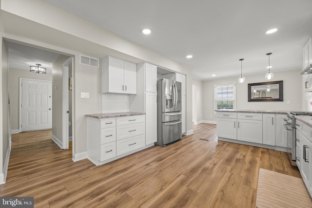 kitchen with visible vents, decorative backsplash, stainless steel appliances, light wood-style floors, and white cabinetry