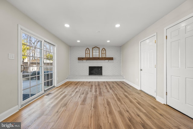 unfurnished living room featuring light wood finished floors, visible vents, a brick fireplace, baseboards, and recessed lighting