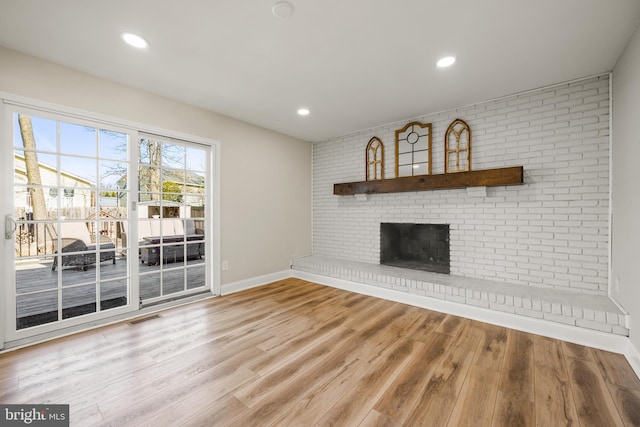 unfurnished living room with wood finished floors, a fireplace, visible vents, and baseboards