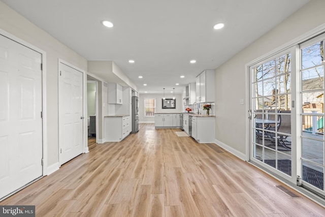 unfurnished living room with light wood finished floors, visible vents, recessed lighting, and baseboards