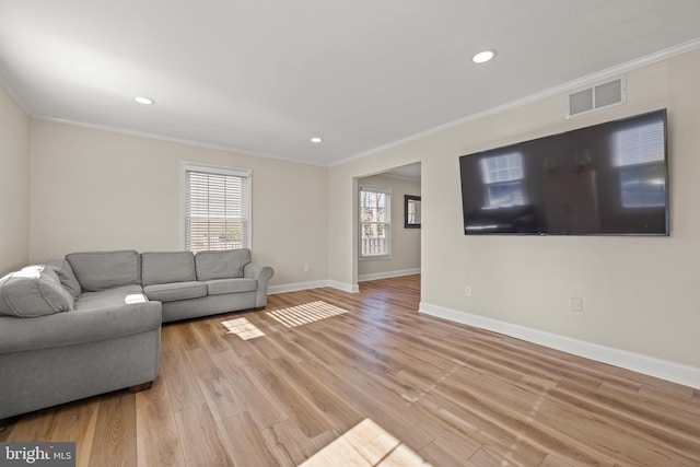 living room featuring light wood-style flooring, baseboards, visible vents, and ornamental molding