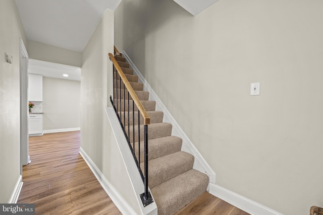 stairs with wood finished floors and baseboards