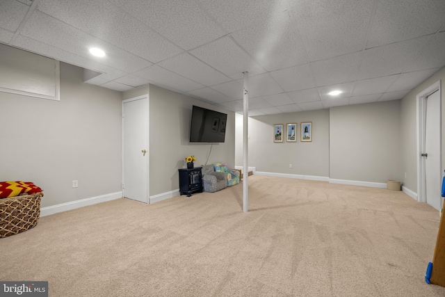 finished basement featuring carpet flooring, a paneled ceiling, and baseboards